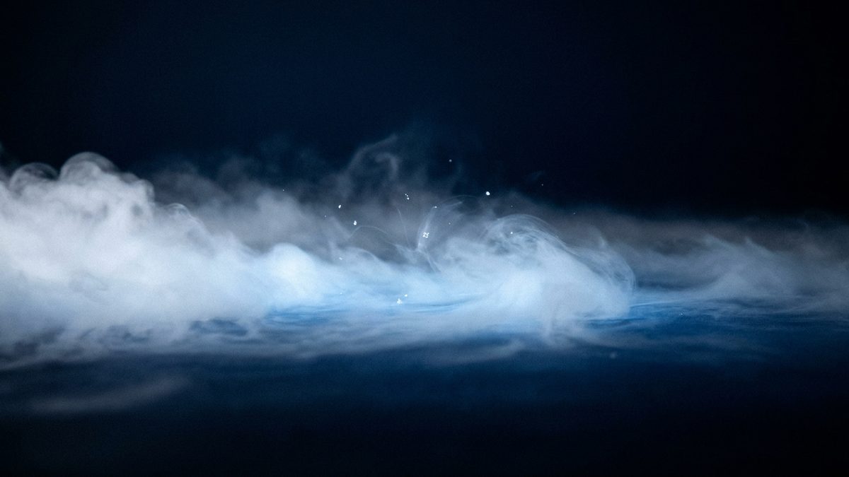 Low dry ice fog rolling across a dark stage floor